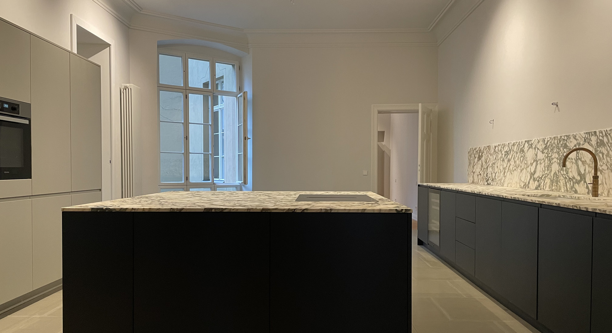 Küche dunkel lackiert, matte Oberflächen, Zeile und Kücheninsel mit italienischer Steinplatte belegt, Einbauschrank hoch , Kücheninsel rechteckig zwei Sitzplätze, Armatur Messing von Quooker, flächenbündiges Kochfeld BORA