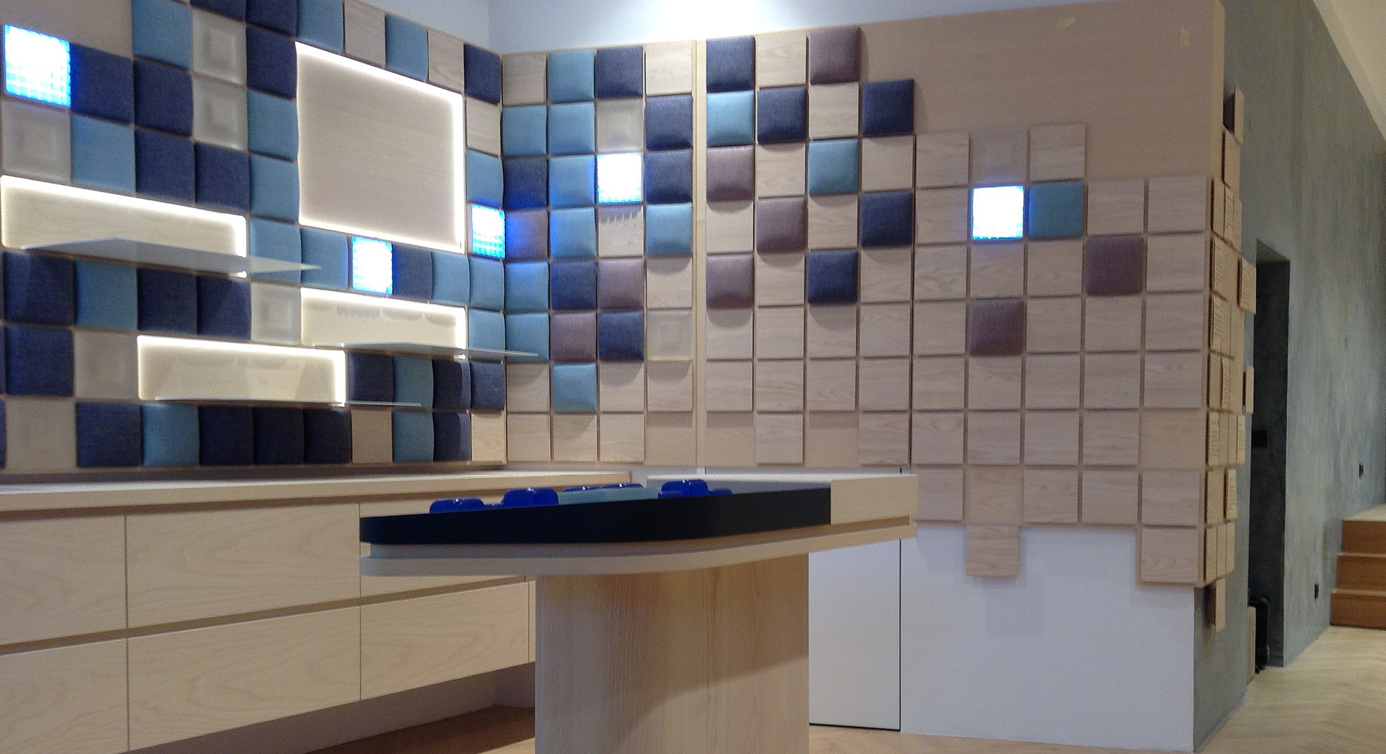 Ladengeschäft, Retail Design, Sideboards mit gebogenen Elementen,  Präsentationsflächen und 3D Reliefs beleuchtet, Polsterelemente mit Kvadrat Stoff, multifunktionales Touchpaneel Tresen, Esche Furnier und Massivholz hell gebeizt und matt lackiert